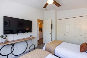 A bedroom with a bed, a TV mounted on the wall, a wooden bench, and a ceiling fan. - Remodeled End Unit | Family Amenities | #609 (Saint George)