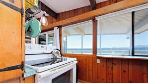A kitchen with wooden walls, a white stove, and a window overlooking a scenic view. - Anna's Bay Beach House, Union (Union)