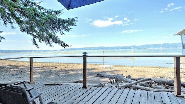 A wooden deck with a railing overlooking a beach and water. - Anna's Bay Beach House, Union (Union)