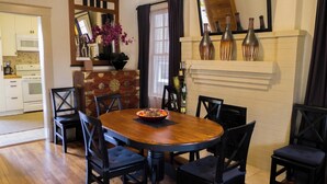 A dining area with a wooden table and chairs, a vase with flowers, and a kitchen in the background. - Cozy Private Cottage in the Heart of Downtown Asheville - 300 5-star reviews! (Asheville)
