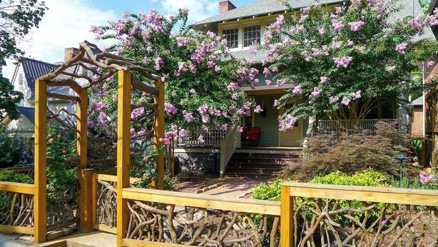 A house with a wooden staircase leading to a porch, surrounded by blooming pink flowers. - Cozy Private Cottage in the Heart of Downtown Asheville - 300 5-star reviews! (Asheville)