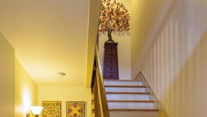 A staircase with wooden steps and a handrail, leading to a landing with a bookshelf and decorative items. - Cozy Private Cottage in the Heart of Downtown Asheville - 300 5-star reviews! (Asheville)