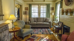A cozy living room with a sofa, armchairs, a coffee table, and a fireplace. - Cozy Private Cottage in the Heart of Downtown Asheville - 300 5-star reviews! (Asheville)