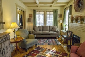 Un salon chaleureux avec un canapé, des fauteuils, un tapis à motifs et une cheminée.