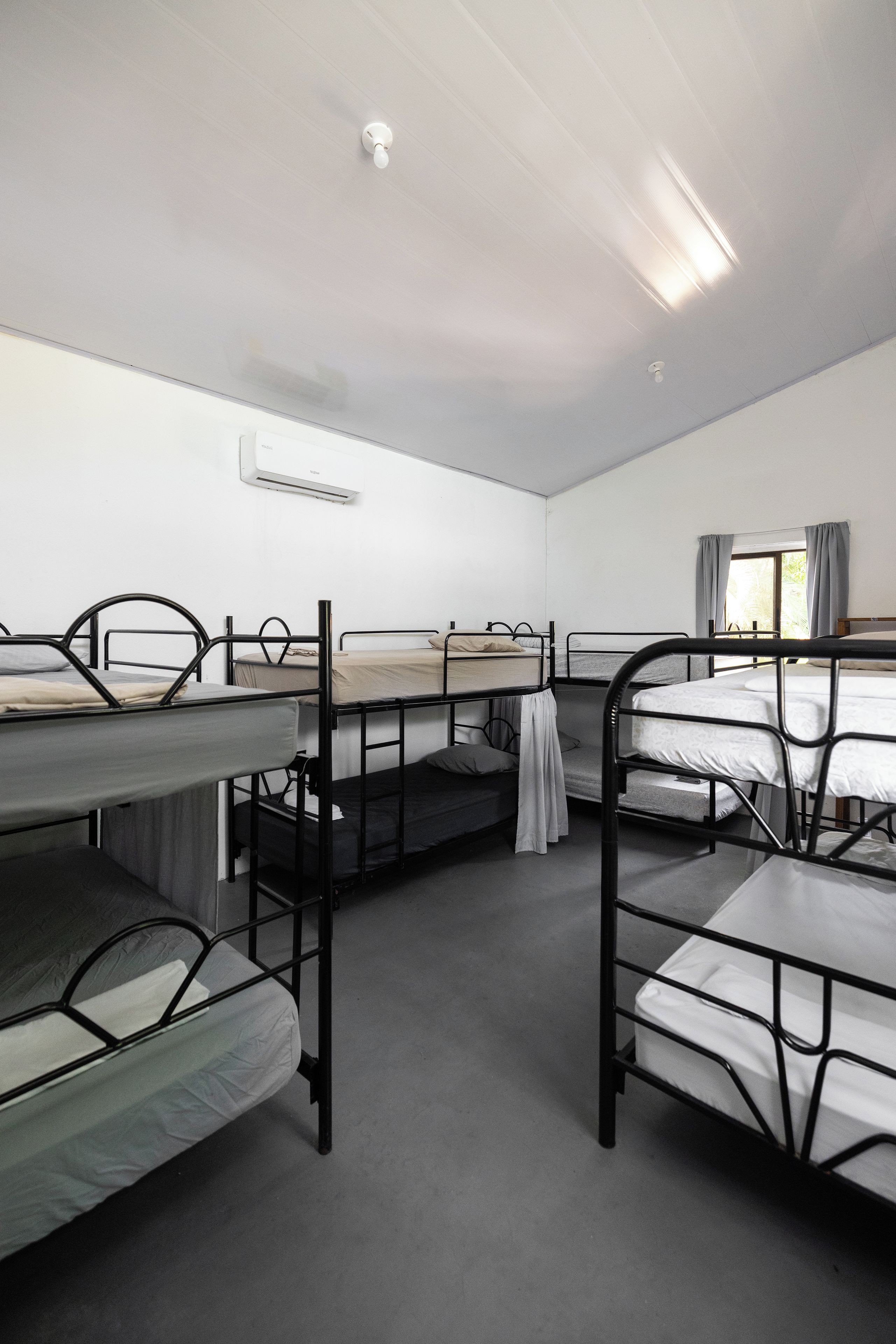 Un dormitorio con literas, una ventana con cortinas y un equipo de aire acondicionado en la pared.