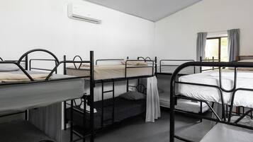 Un dormitorio con literas, una ventana con cortinas y un equipo de aire acondicionado en la pared.