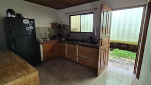 Cucina compatta con frigorifero, mobili in legno, un piano di lavoro e una finestra.