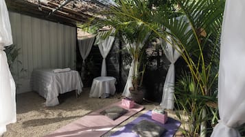 A room with a bed, a small table, and a yoga mat area.