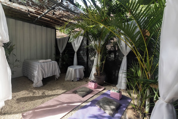 A room with a bed, a small table, and a yoga mat area.