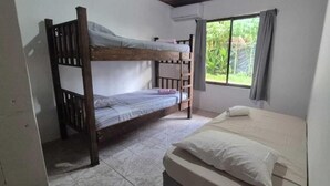 Una stanza con un letto a castello, un letto singolo e una finestra con tende.