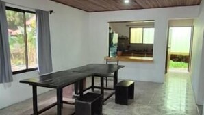 Un'ampia stanza con soffitto in legno, un tavolo grande con panche e vista sull'esterno da una finestra.