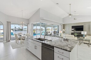 Second kitchen or kitchenette area with white cabinetry, granite island, and views of the canal through full-length windows - Welcoming Canal View Villa with Direct Access to the Gulf (Cape Coral)