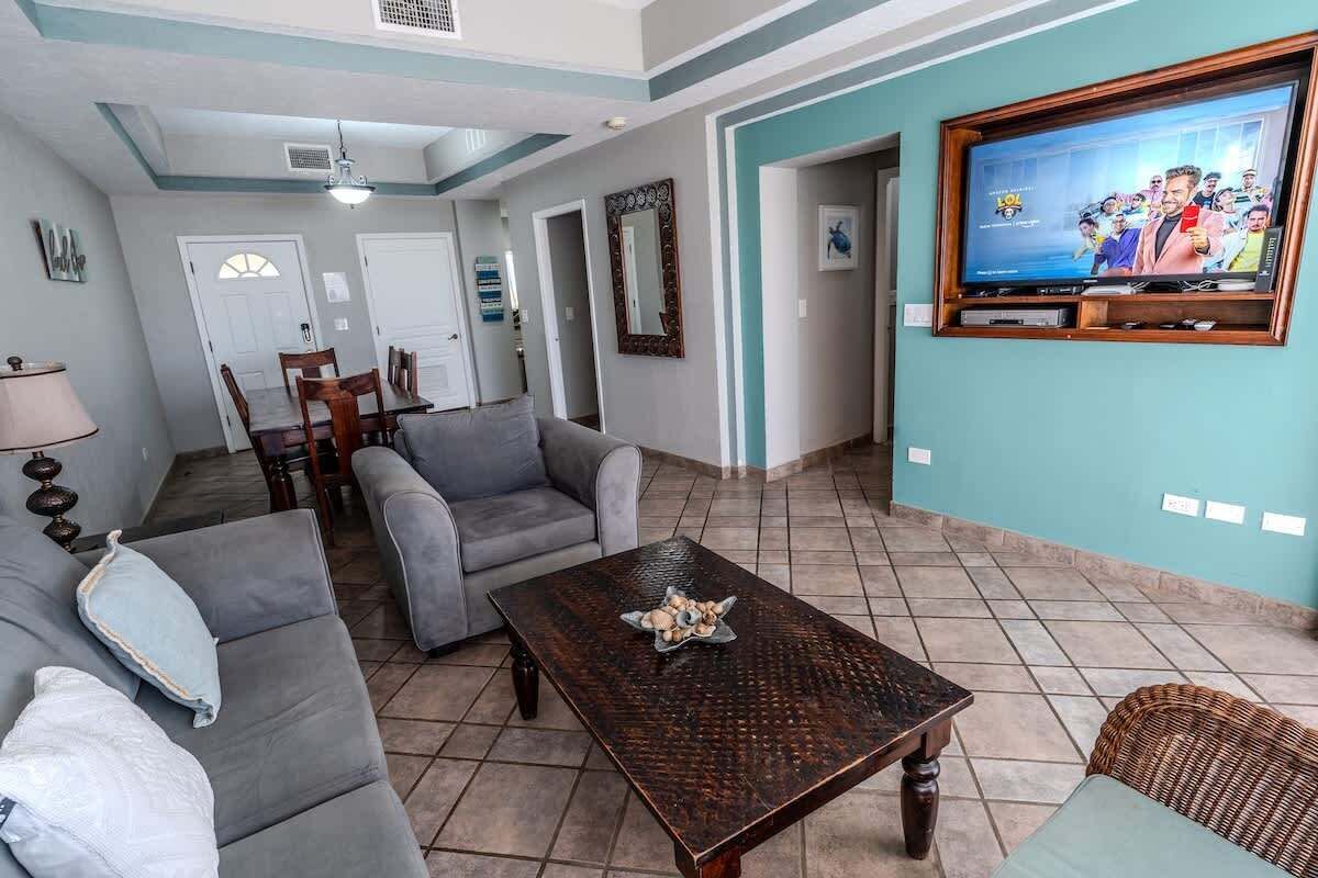 Una sala de estar con un sofá, una mesa de centro, un televisor y un comedor con sillas y una mesa.