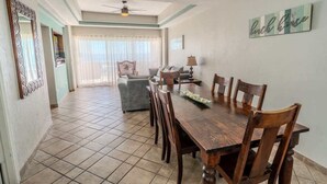 A dining area with a wooden table and chairs, a ceiling fan, and a 'Beach House' sign on the wall. - Bonita 503A, Las Palmas Resort (Puerto Peñasco)