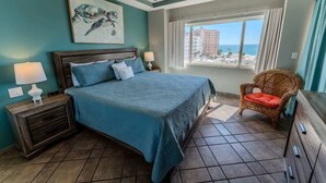 A bedroom with a bed, nightstands, a chair, a window with a view, and a painting on the wall. - Bonita 503A, Las Palmas Resort (Puerto Peñasco)