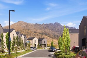 A residential street with modern houses, a clear sky, and mountains in the background. - Cynthia's Home away from Home (Queenstown)