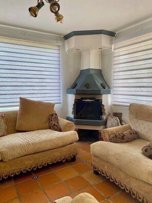 Una sala de estar con dos sofás color beige, una chimenea y una lámpara colgante.