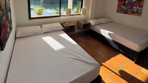 Camera da letto con due letti, un'ampia finestra vista su lago e bosco, e una ventola a soffitto.