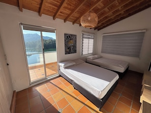 Un dormitorio con cama, una ventana con persianas, una puerta y vistas a las montañas a través de una puerta corredera.