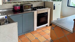 Una cucina compatta con mobili in legno, un forno a microonde, un piano cottura a gas e un frigorifero.