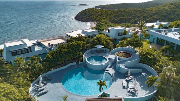 Ein modernes Resort mit großem Pool, mehreren Liegebereichen und Blick auf den Ozean.