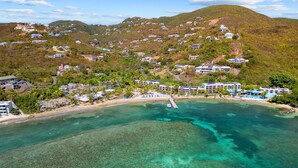 Ein Luftbild eines Küstenresorts mit klarem türkisblauem Wasser, einem Sandstrand und mehrstöckigen Gebäuden.