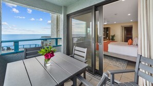 Ein Balkon mit Tisch und Stühlen, einem Blumenstrauß und Blick auf das Meer.