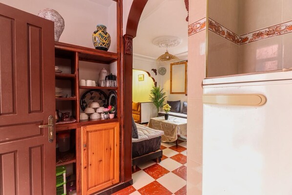 A room with a wooden cabinet, a sofa, a table with a vase, and a mirror on the wall.