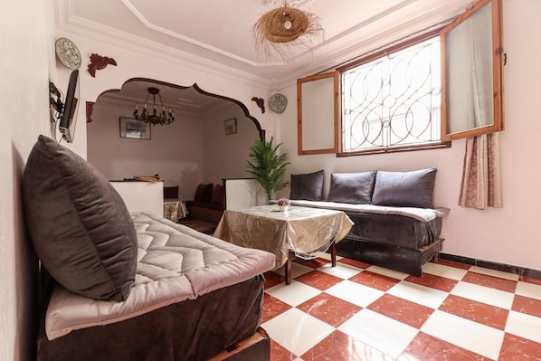 A cozy living room with a checkered floor, a sofa, a table with a vase, and a decorative mirror.