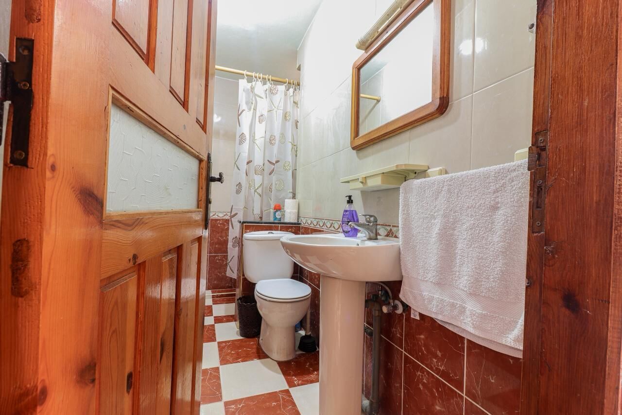A bathroom with a wooden door, a white sink, a toilet, and a shower curtain.