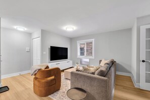 A modern living room with a flat-screen TV, a sofa, a coffee table, and a patterned rug. - Retreat Near Andersonville 3BR Newly Remodeled (Chicago)