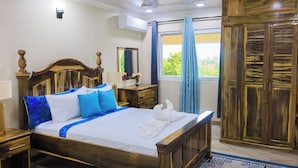 A hotel room with a wooden bed, a ceiling fan, a nightstand, a dresser, and a window with curtains. - Sy Villa (Choiseul)