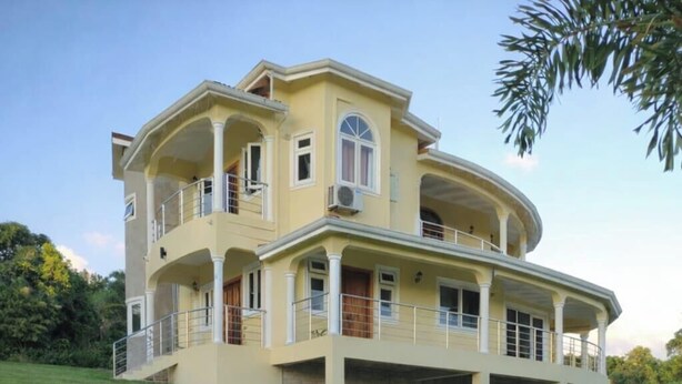 A two-story building with a balcony on the upper floor, surrounded by greenery. - Sy Villa (Choiseul)