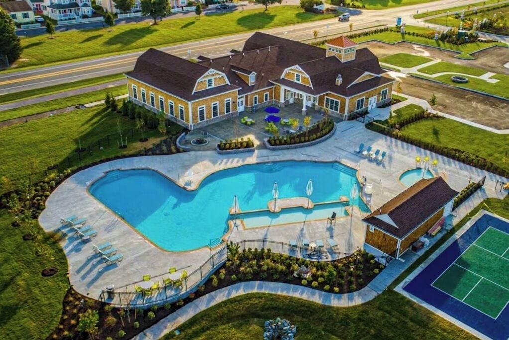A large house with a swimming pool, tennis court, and a well-maintained lawn.