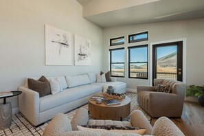 Ein modernes Wohnzimmer mit Sofa, Sessel, Couchtisch und Kunstwerk an der Wand.