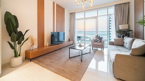 Una sala de estar moderna con una televisión de pantalla plana, una mesa de centro, un sofá y un amplio ventanal con vistas.