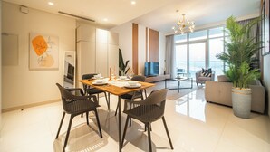 Una sala de estar moderna con sofá, mesa de comedor con sillas, televisor y ventana grande.