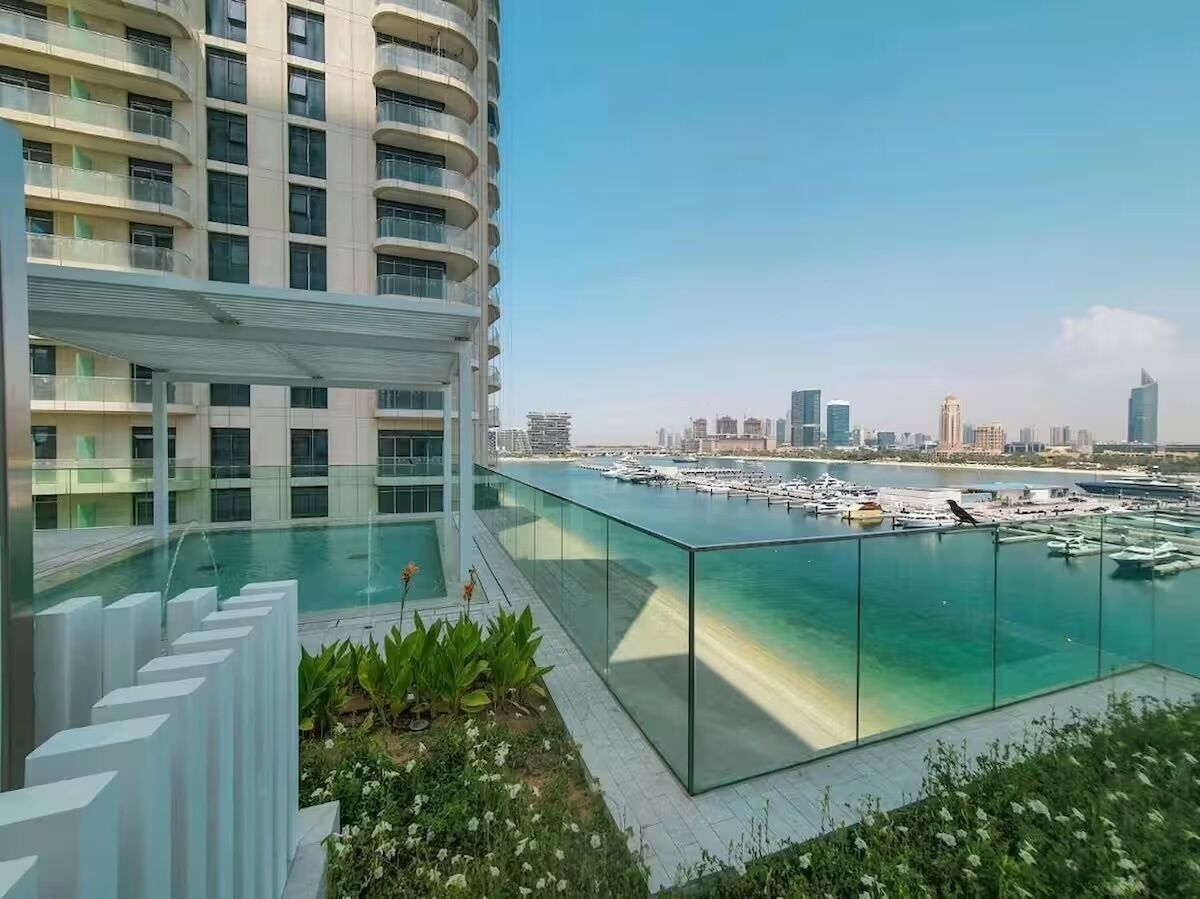 Ein modernes Gebäude mit einem gläsernen Pool und Blick auf eine Marina mit Booten.