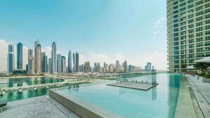 Una piscina en la azotea con vistas a un horizonte urbano, arquitectura moderna y cielo despejado.