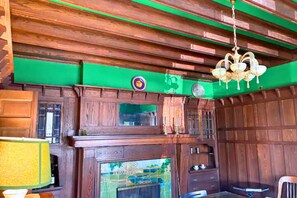 Une pièce avec des boiseries, un lustre, une cheminée et un mur vert.