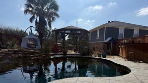 Un patio trasero con piscina, pérgola y valla de madera.