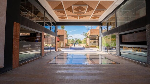 A spacious atrium with a central fountain, glass storefronts, and a modern ceiling design. - Elegant Apartment with Panoramic View  (Marrakech)