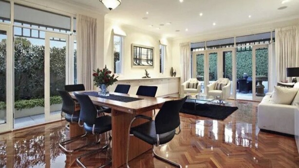A spacious room with a large wooden dining table, black chairs, and a glass coffee table. There are two white sofas and a large window with a view of greenery. - Luxurious Kew House - 5 min walk to cafes and restaurants (Kew)