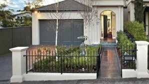 A two-story house with a front entrance, a garage, and a well-maintained garden. - Luxurious Kew House - 5 min walk to cafes and restaurants (Kew)
