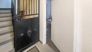 Ein Zimmer mit einem schwarzen Metallgitter, einer weißen Tür und einem kleinen Fenster.