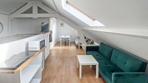 Eine kleine, moderne Küche mit Essbereich und einem grünen Sofa.