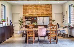 A kitchen with a brick wall, a refrigerator, and a dining area with chairs and a table. - Gorgeous home in Auvilliers with WiFi (Auvilliers)