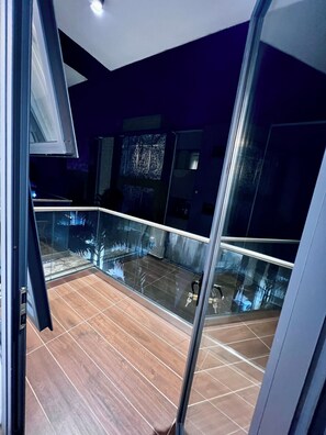 A modern interior with a glass balcony, wooden flooring, and contemporary design elements. - Golden luxury studio apartment at Cantonments+Pool (Accra)