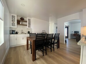 A modern kitchen with white cabinets, a dining table with chairs, and a visible kitchen island.