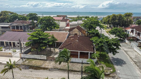 A coastal residential area with houses, a paved road, and a view of the ocean.